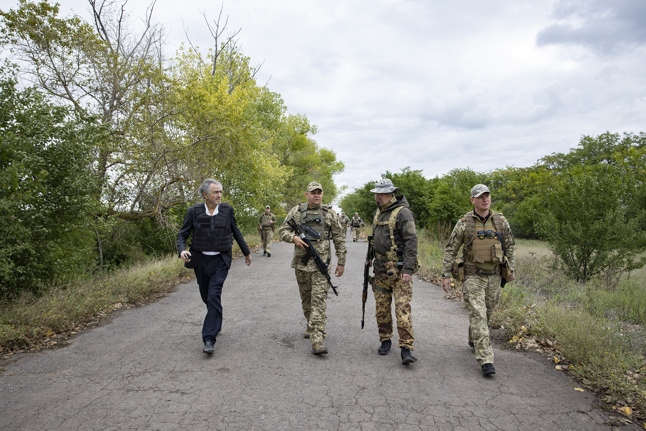Bernard-Henri Lévy sur le front de Kherson en Ukraine, il marche sur un route avec des militaires.