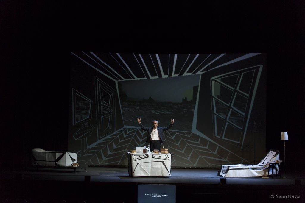 Bernard-Henri Lévy joue sa pièce « Looking for Europe » au Teatre Coliseum de Barcelone, il est debout seul en scène derrière un bureau.