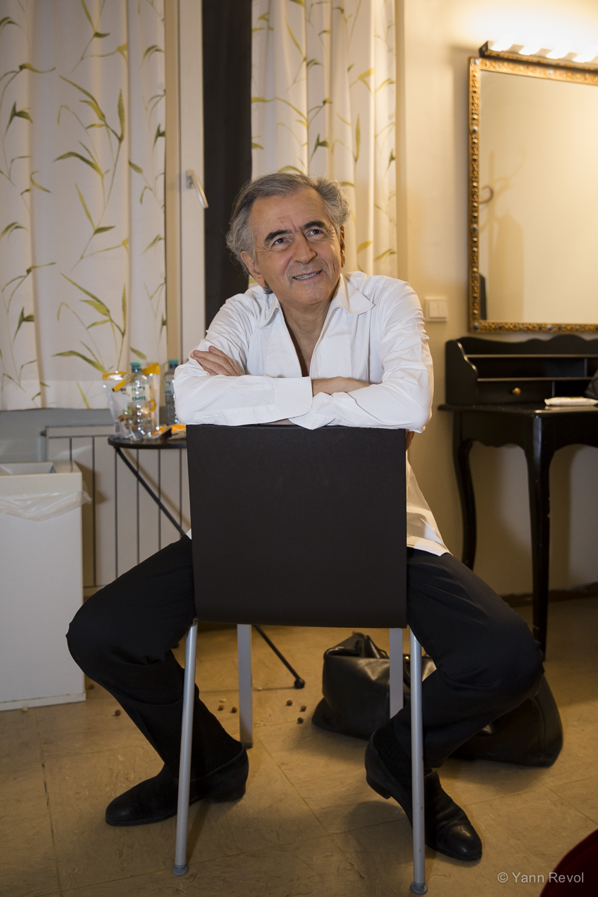 Bernard-Henri Lévy dans sa loge après sa performance dans « Looking for Europe », il est assis sur une chaise.
