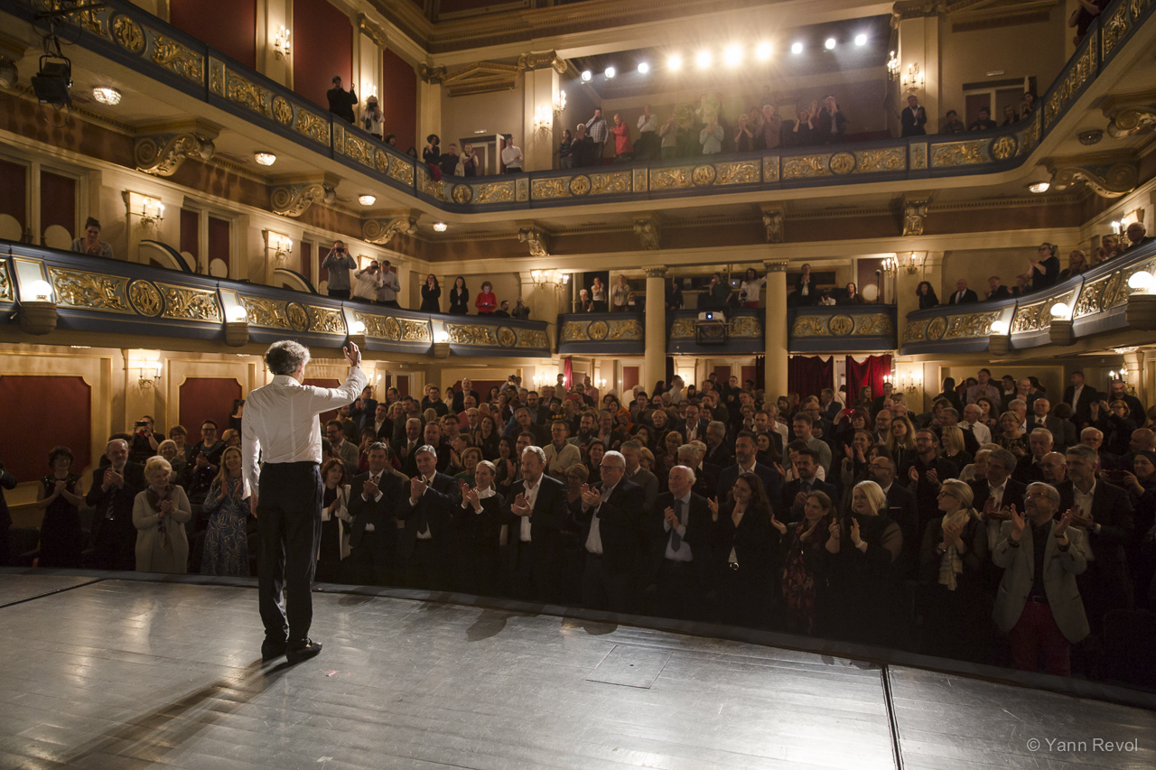 Bernard-Henri Lévy à l'avant scène du Théâtre National de Sarajevo salue le public qui applaudit debout.