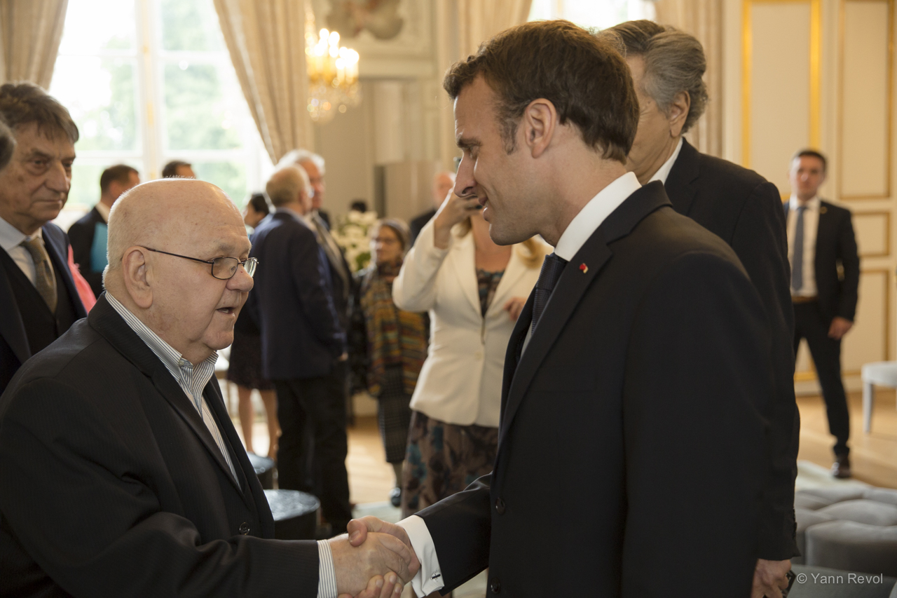 Abdulah Sidran rencontre Emmanuel Macron dans un salon de l'Élysée, ils se serrent la main.