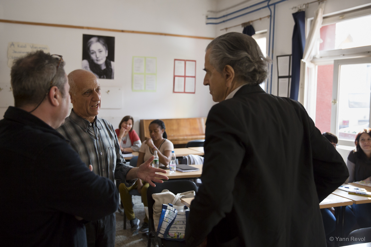 Bernard-Henri Lévy dans une salle de classe pour adultes, il parle avec un professeur.