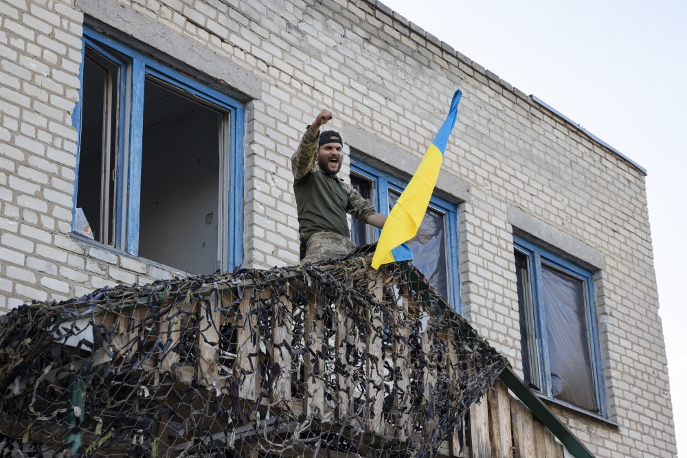 Un militaire sur un balcon porte un drapeau ukrainien.