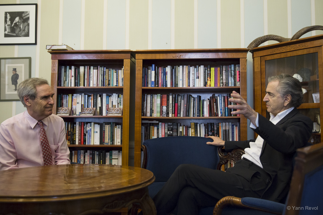 Bernard-Henri Lévy rencontre le recteur du CEU Michael Ignatieff à Budapest, dans un salon dans lequel il y a des bibliothèques.