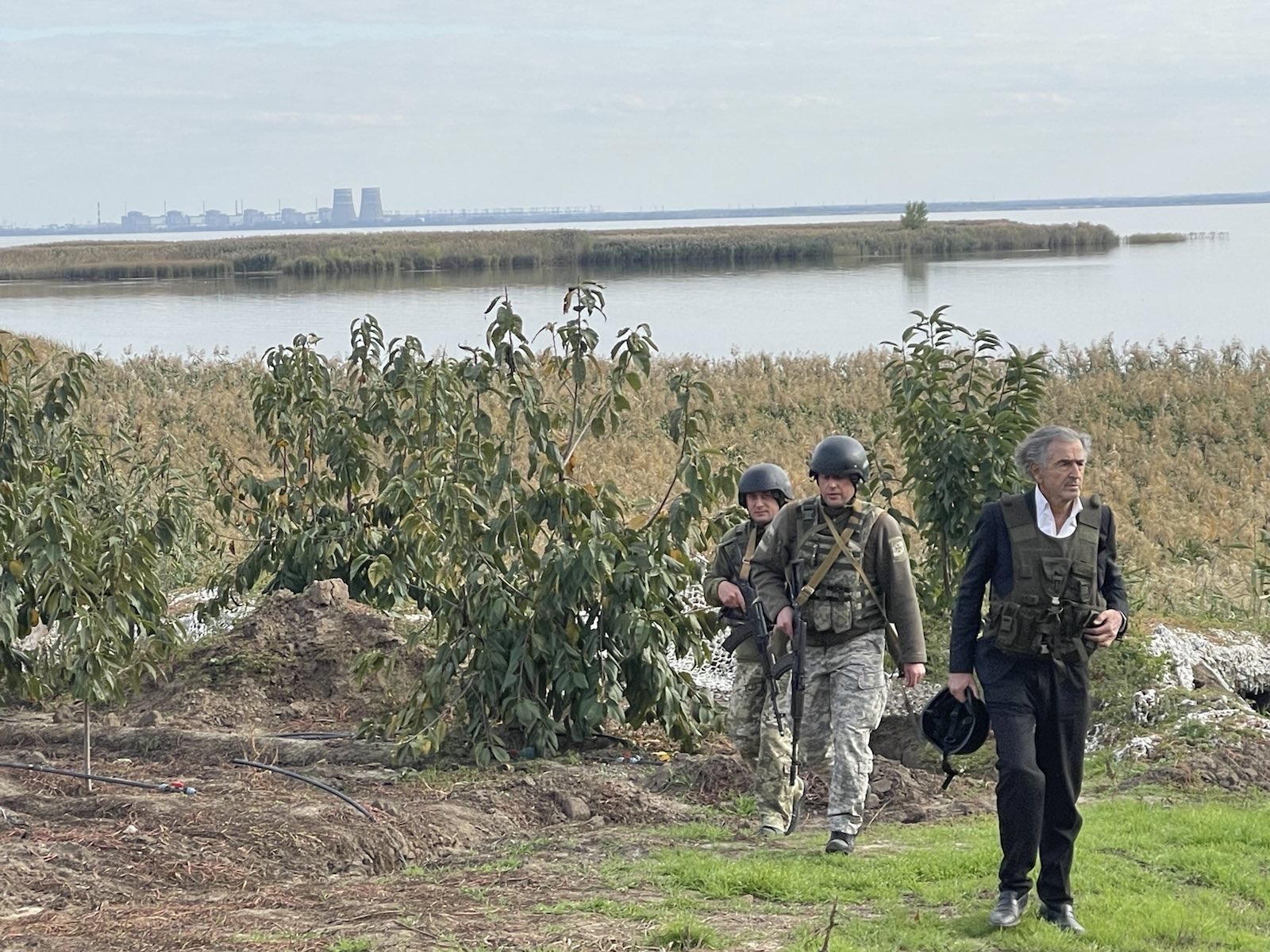 Bernard-Henri Lévy aux abords de la centrale de Zaporijjia, il est debout au bord de l'eau avec deux militaires ukrainiens.