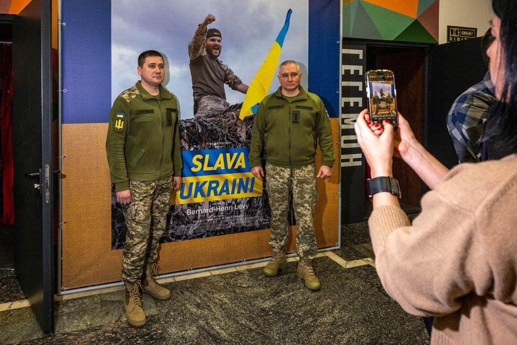 Deux militaires ukrainiens posent devant l'affiche du film de BHL « Slava Ukraini » à Kiev.