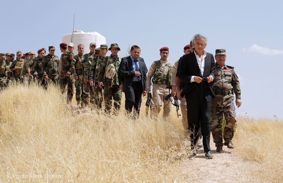 Bernard-Henri Lévy au Kurdistan irakien avec les Peshmergas. Ils marchent en file indienne, BHL en tête