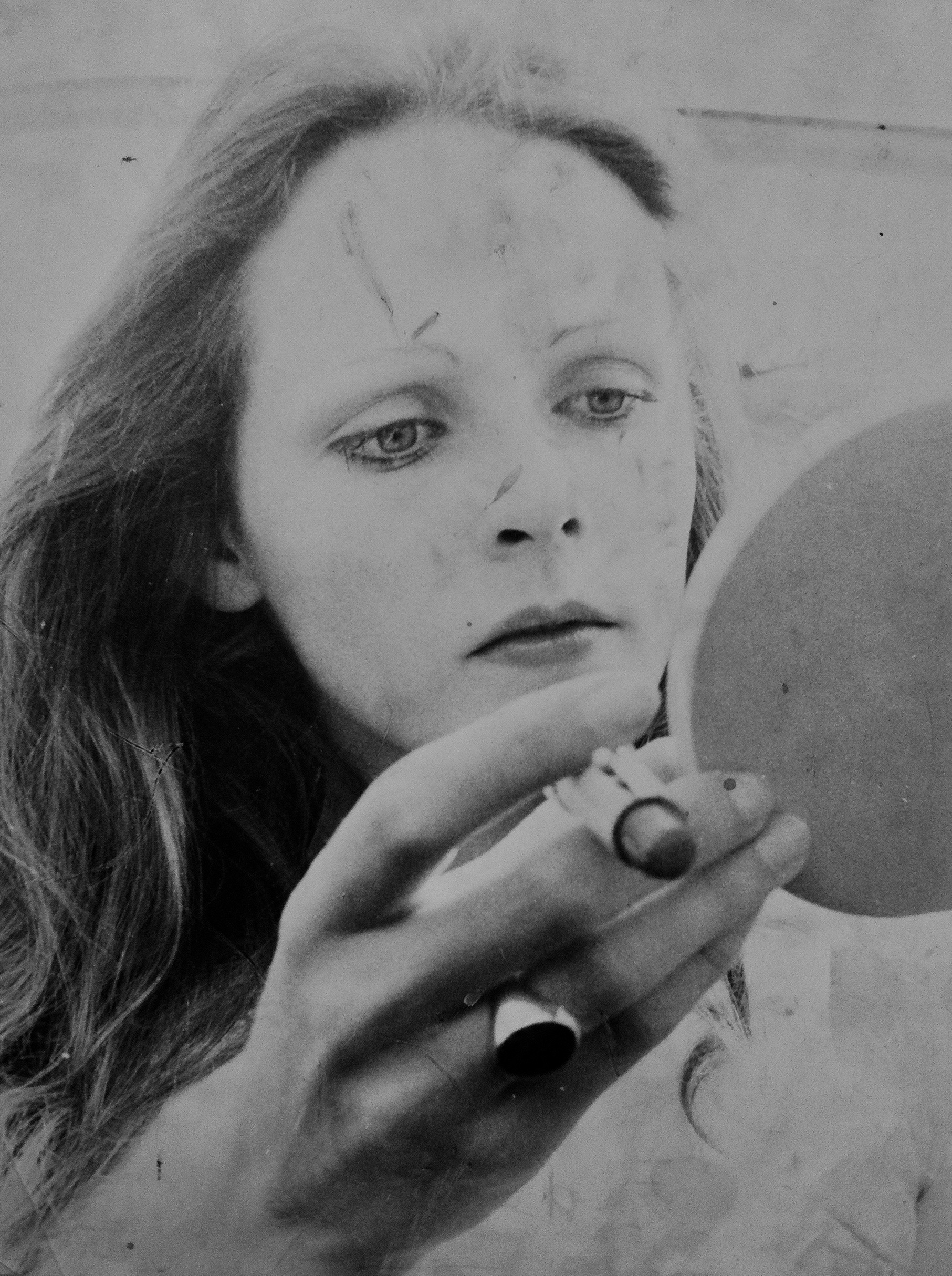 Portrait d'Isabelle Doutreluigne en noir et blanc, elle tient un miroir et un rouge à lèvres pour se maquiller.
