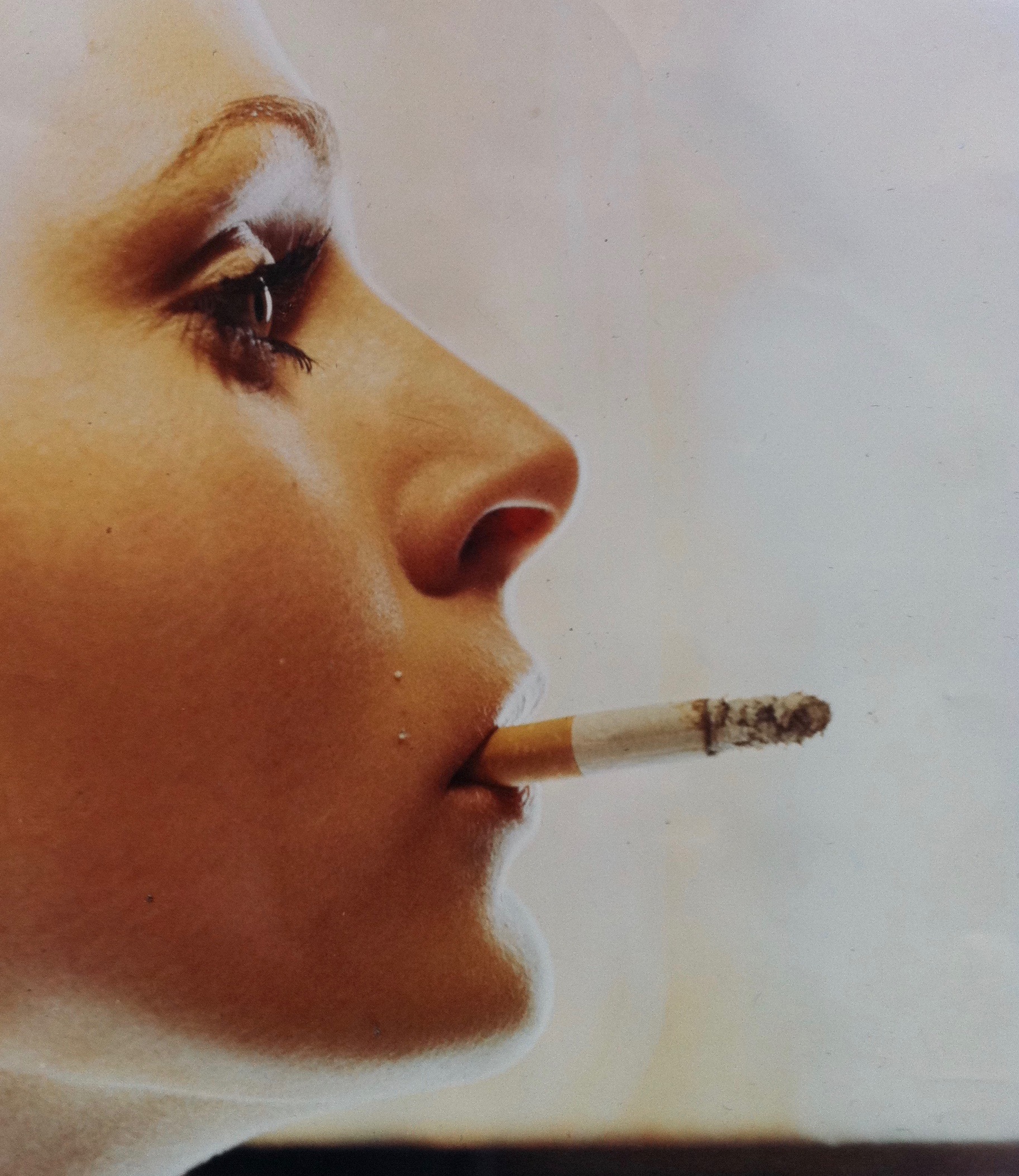 Portrait d'Isabelle Doutreluigne en couleurs, de profil, elle fume une cigarette.