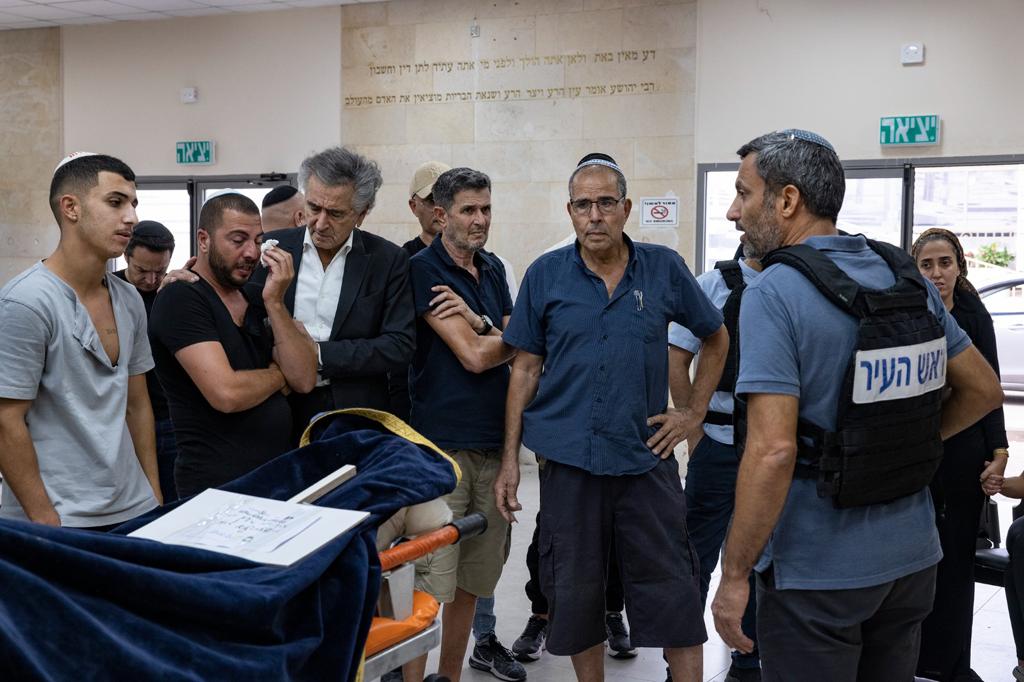 Bernard-Henri Lévy lors des funérailles du chef des pompiers de Sderot. Devant le corps du défunt , recouvert d'un linceul, il est avec les membres de la famille et de l'entourage qui pleure.