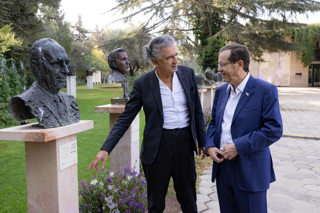 BHL et Issac Herzog, 11ème président de l'État d'Israël, à Jérusalem, devant un buste de Shimon Pérès, dans un jardin.