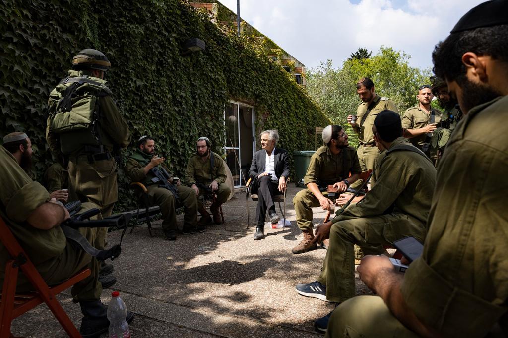 À Kfar Aza, BHL suit une unité de la Zacca. ils sont assis sur des chaises, en cercle, devant une maison.