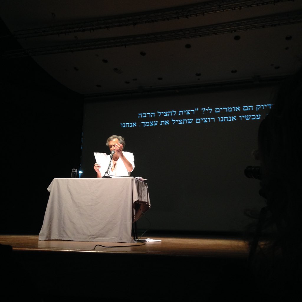 Bernard-Henri Lévy lit des extraits de son livre, « L’Esprit du Judaïsme », au Musée d’Art de Tel-Aviv. Il est seul sur scène, assis derrière une table, et il parle dans un micro.