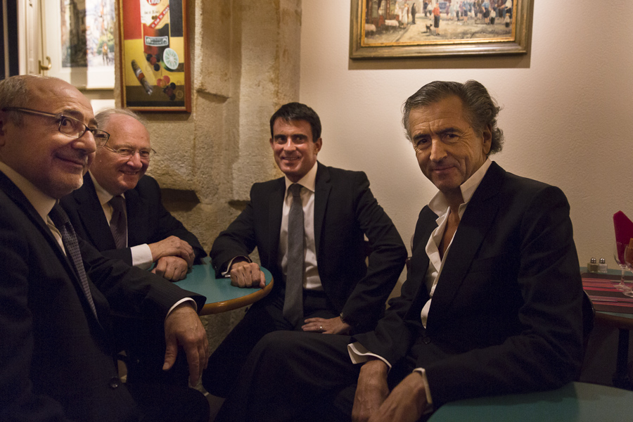 Manuel Valls et Bernard-Henri Lévy sont autour d'une table dans un café avec deux autres hommes.