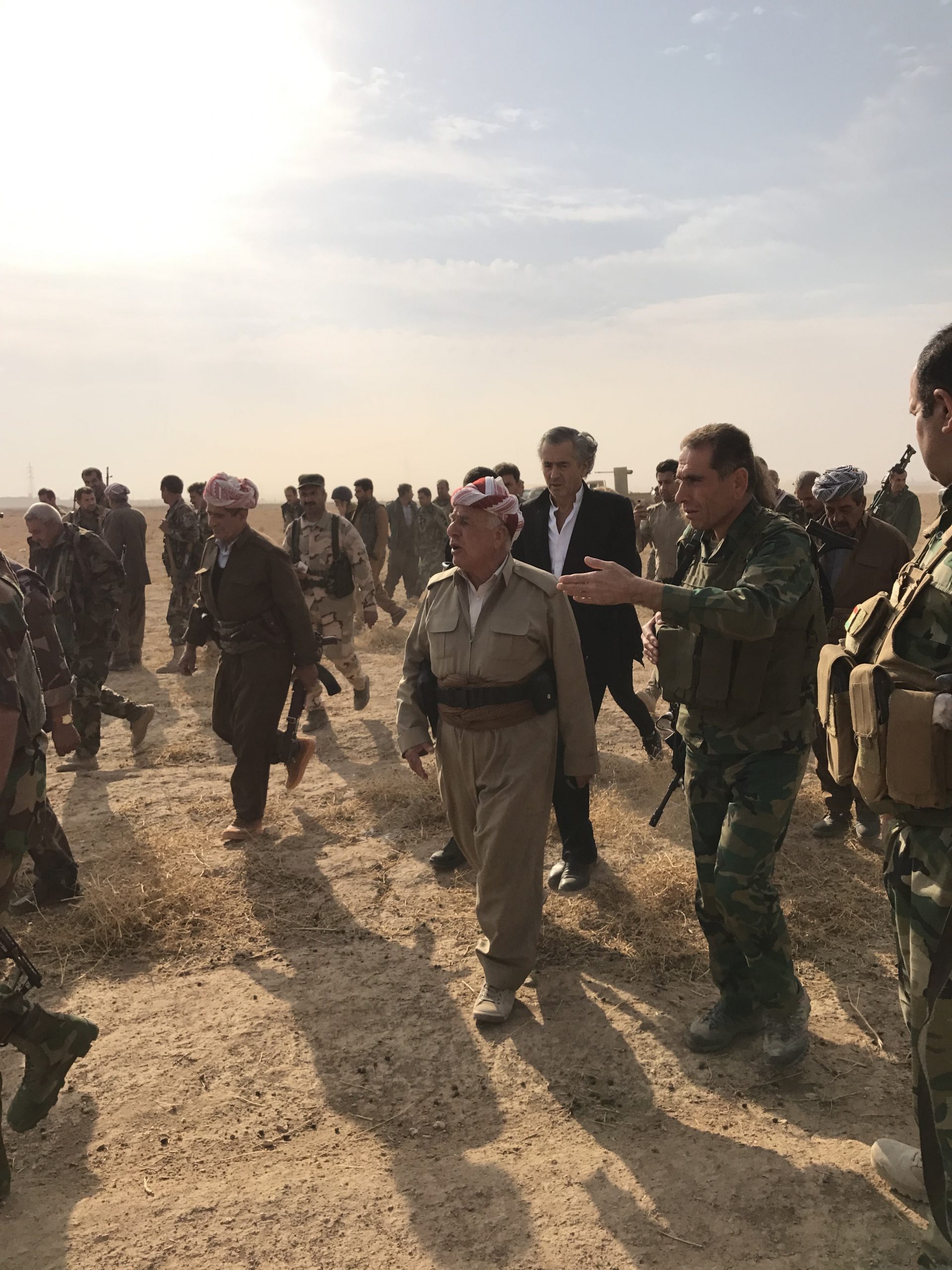 Bernard-Henri Lévy avec les Peshmergas, sur front du Kurdistan irakien, lors de la bataille de Mossoul. Le philosophe marche dans un no mans land au milieu de nombreux militaires.