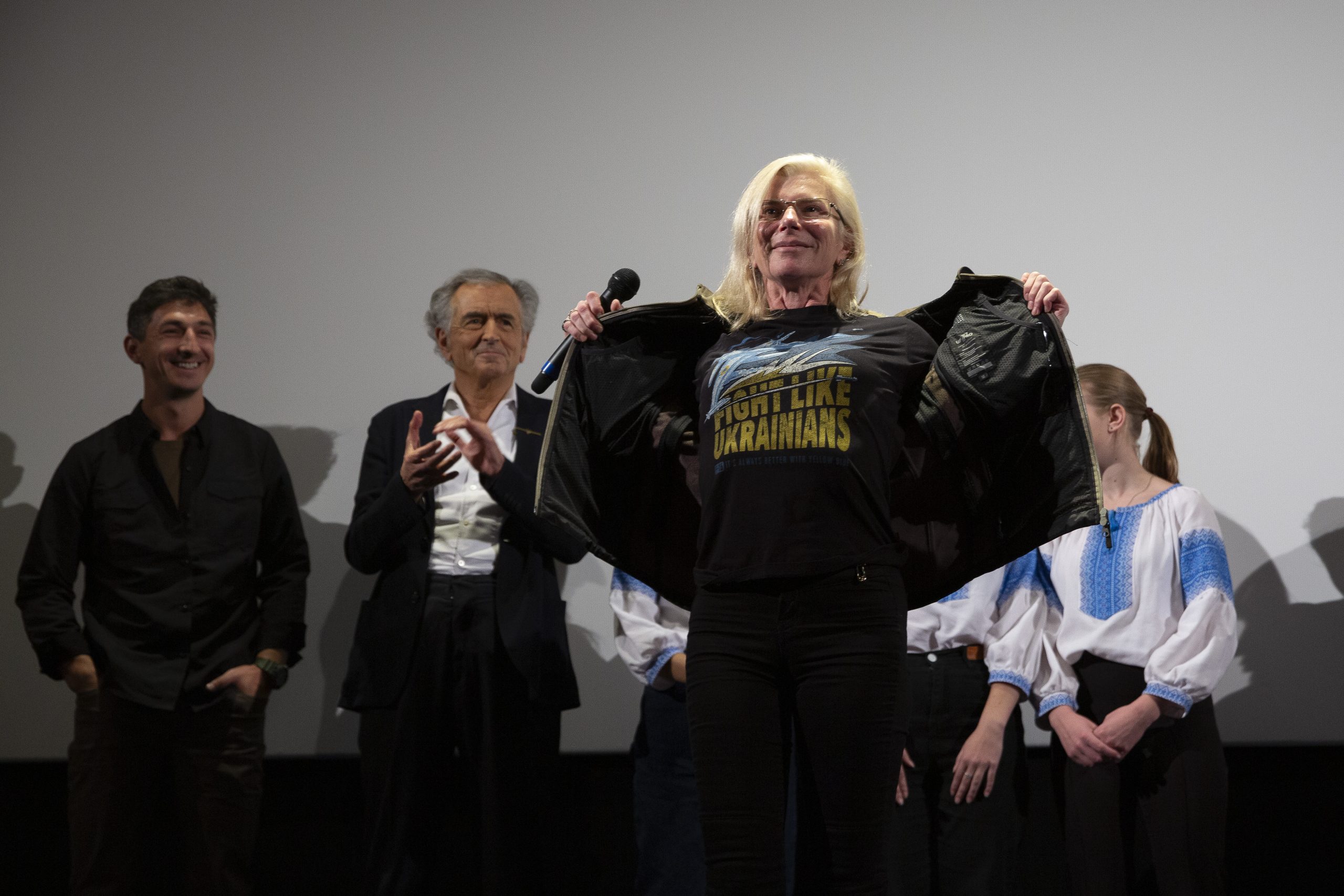 Taïra sur la scène du cinéma le Balzac, à l'issue de la projection du film de BHL. Elle montre son t-shirt sur lequel on peut lire "Fight Like Ukrainians". Derrière on voit Vitaly Paly, Bernard-Henri Lévy et trois petites filles.