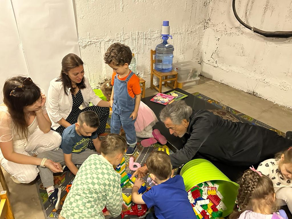 Dans une cave pour fuir abriter des bombardements Bernard-Henri Lévy jour avec des enfants sur un tapis de jeux