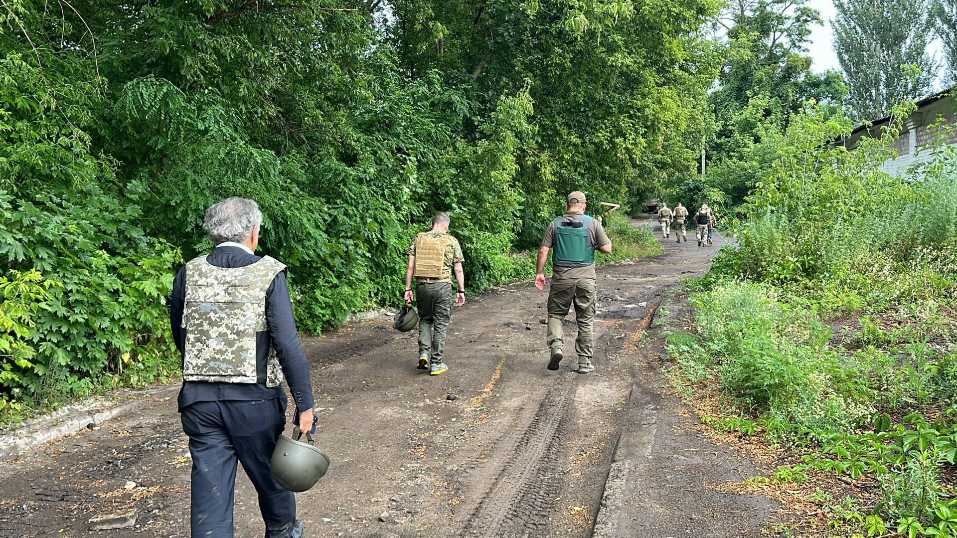 Dans le Donbass, vers Lyman, BHL est avec les soldats ukrainiens, ils marchent dans la nature sur un chemin de terre, on les voit de dos.