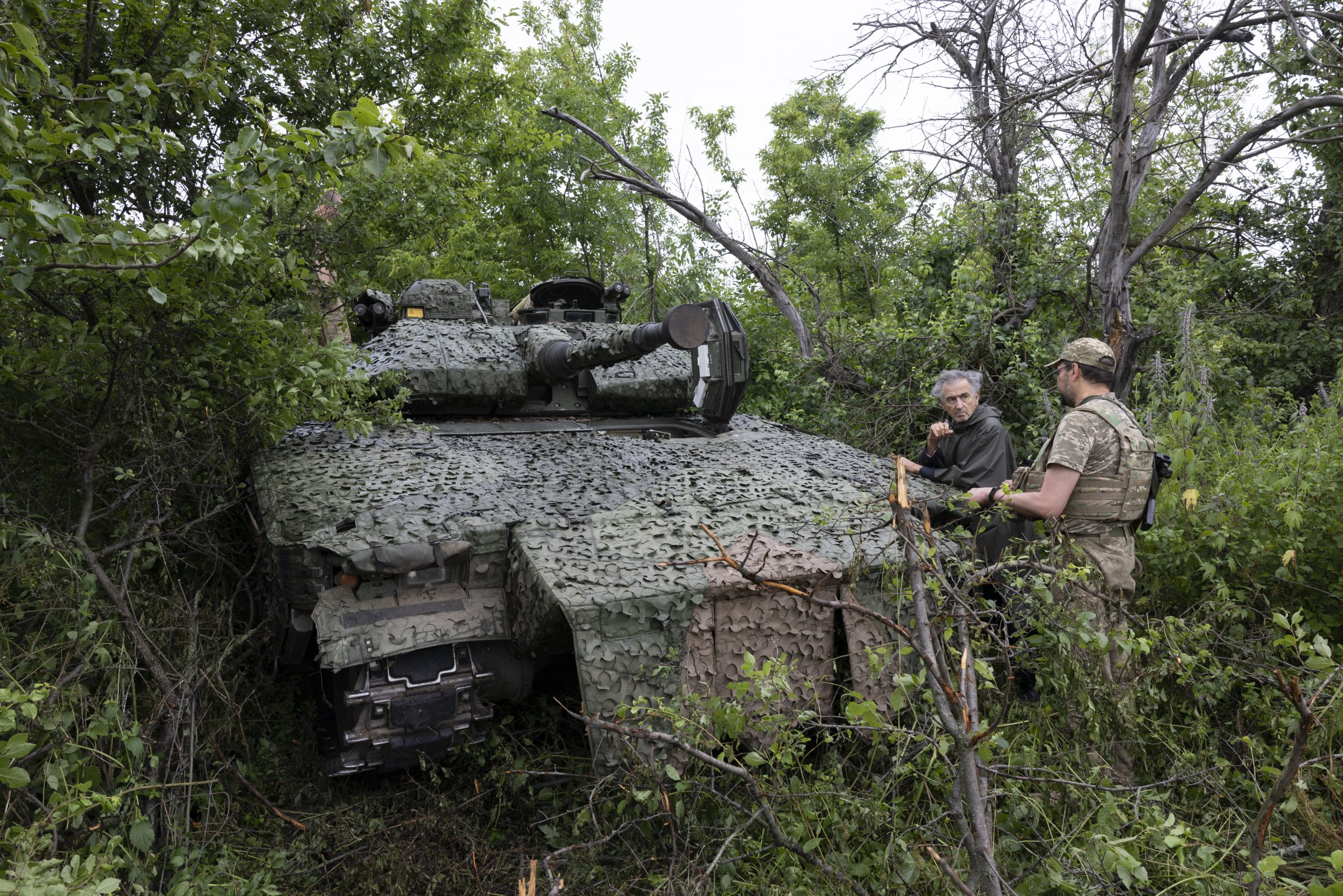 Un char ukrainien près de Lyman, il est camouflé dans les buissons. Bernard-Henri Lévy est debout à côté du char avec un soldat ukrainien.