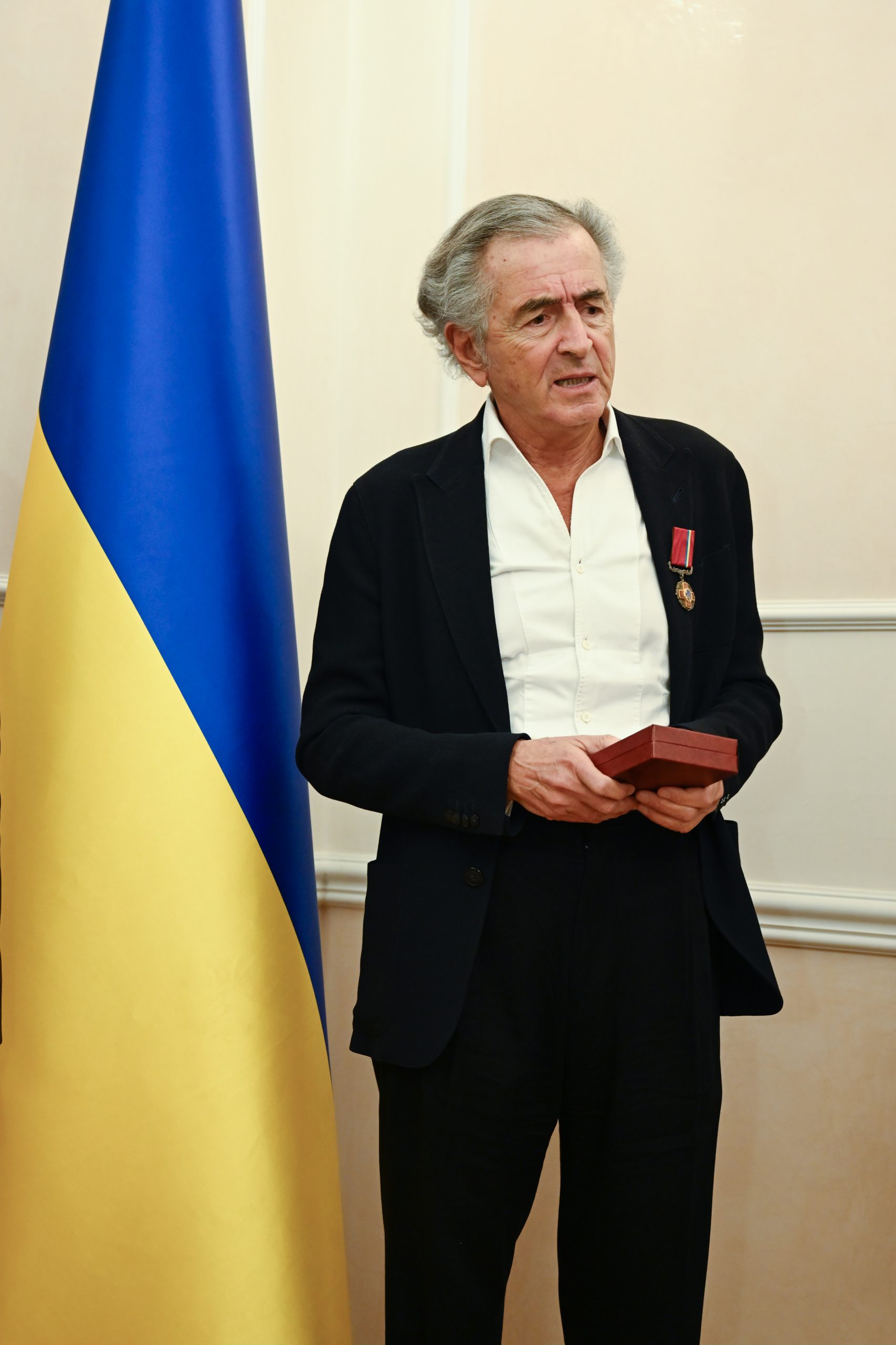 BHL vient de recevoir l'insigne de Chevalier de l'Ordre du Mérite d'Ukraine. Il prononce un discours devant un drapeau ukrainien