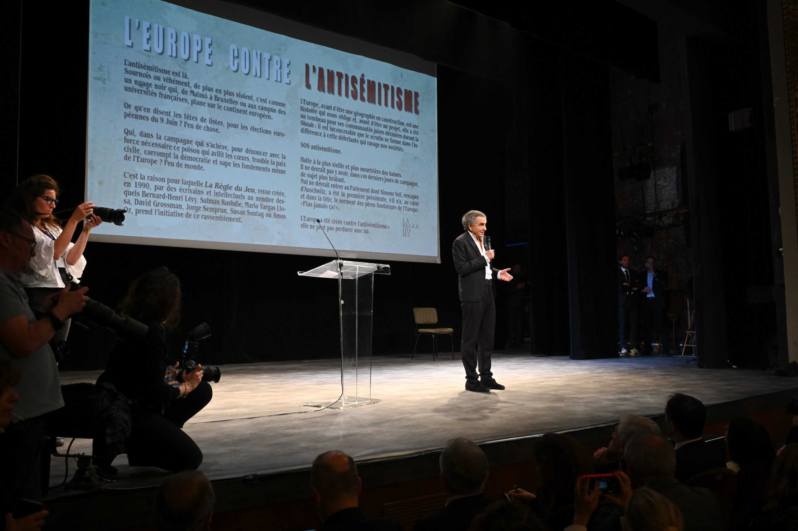 Bernard-Henri Lévy au Théâtre Antoine, il est seul sur scène et parle dans un micro.