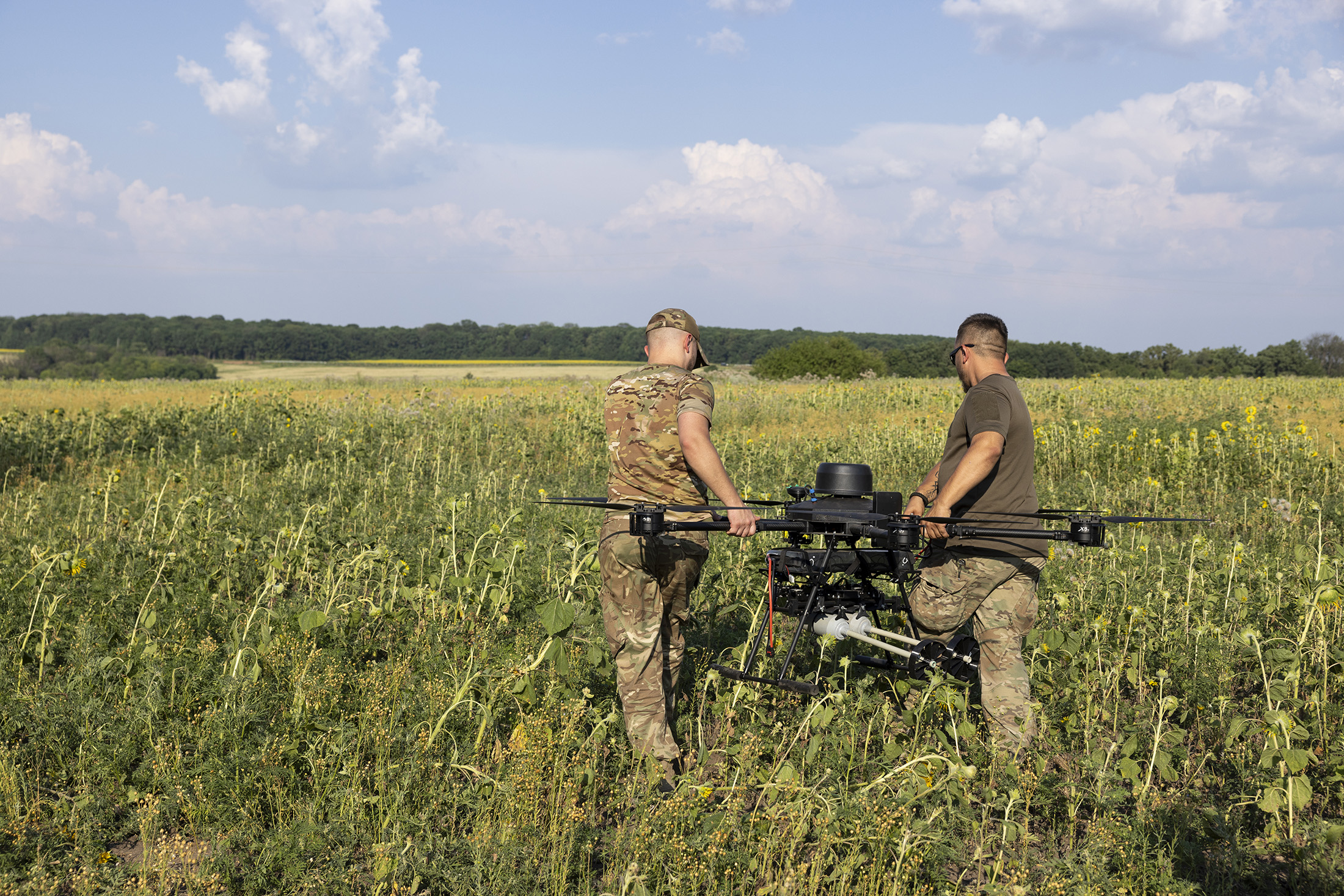 Des membres du bataillon de drones Achilles, qui fait partie de la 92e brigade ukrainienne, préparent un drone près de Kharkiv, dans un champ.